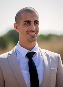 Portrait of a confident businessman smiling in a suit outdoors on a sunny day.
