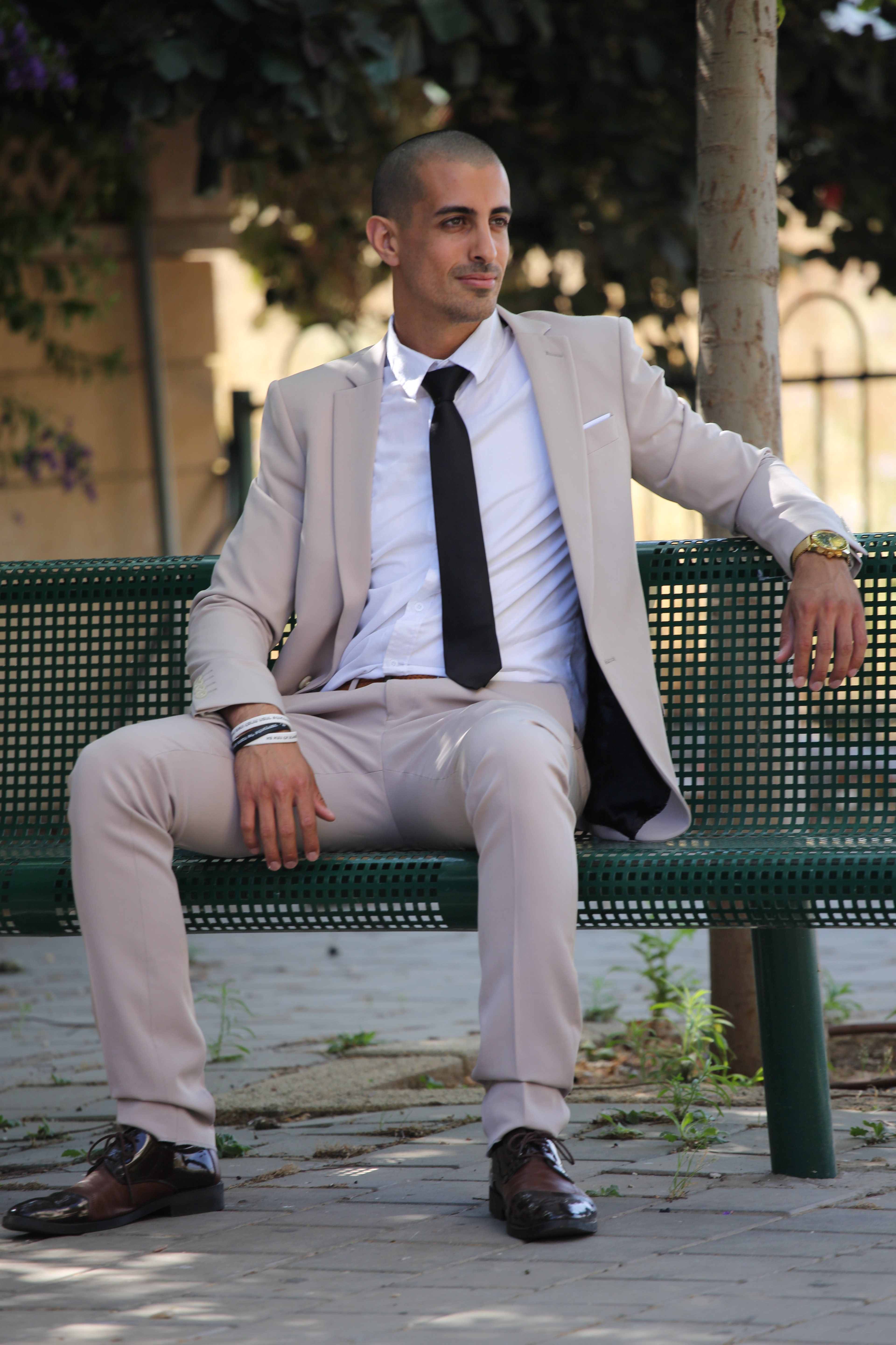 A confident businessman in a stylish suit sits on a bench, embodying success and leadership.