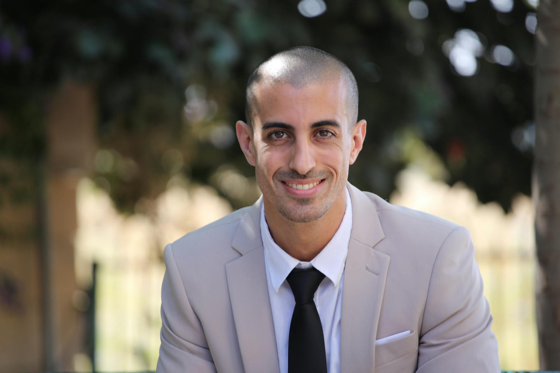 Portrait of a smiling businessman in a light suit, showcasing confidence and professionalism outdoors.