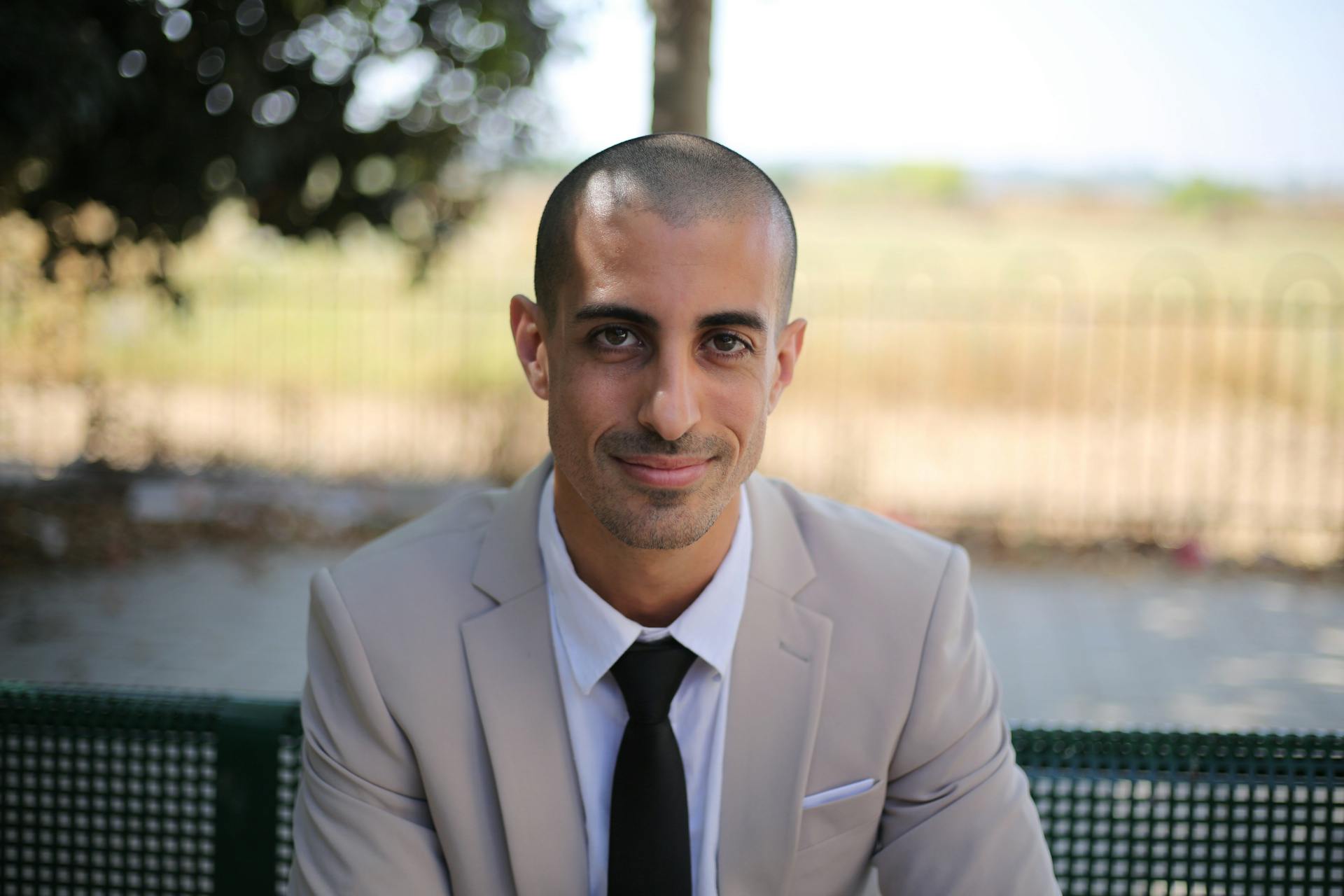 Portrait of a confident businessman in a suit, sitting outdoors with a professional smile.