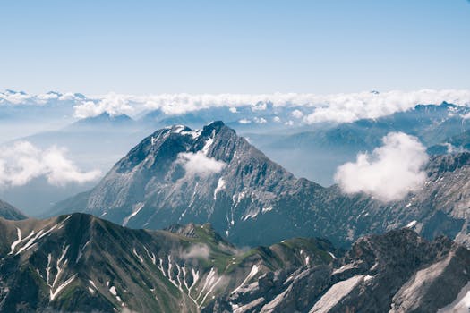 Serene aerial view of alpine mountain peaks shrouded in clouds and sunlight in Bavaria, Germany.