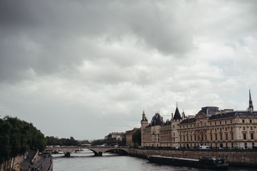 Scenic view of the historic Conciergerie and Seine River in Paris, France on an overcast day.