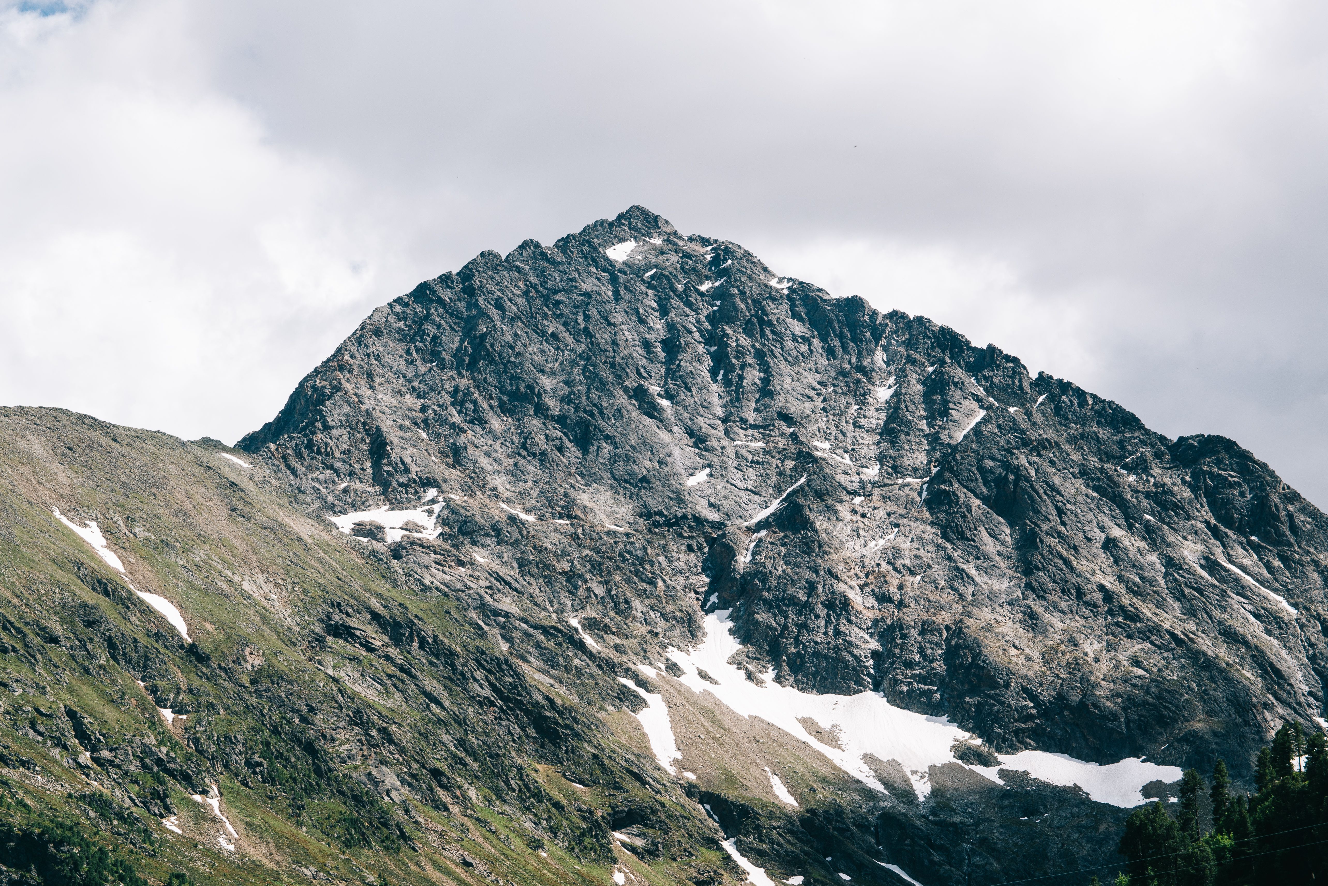 Breathtaking view of a snow-capped mountain peak under a cloudy sky, showcasing natural beauty.