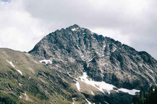 Breathtaking view of a snow-capped mountain peak under a cloudy sky, showcasing natural beauty.