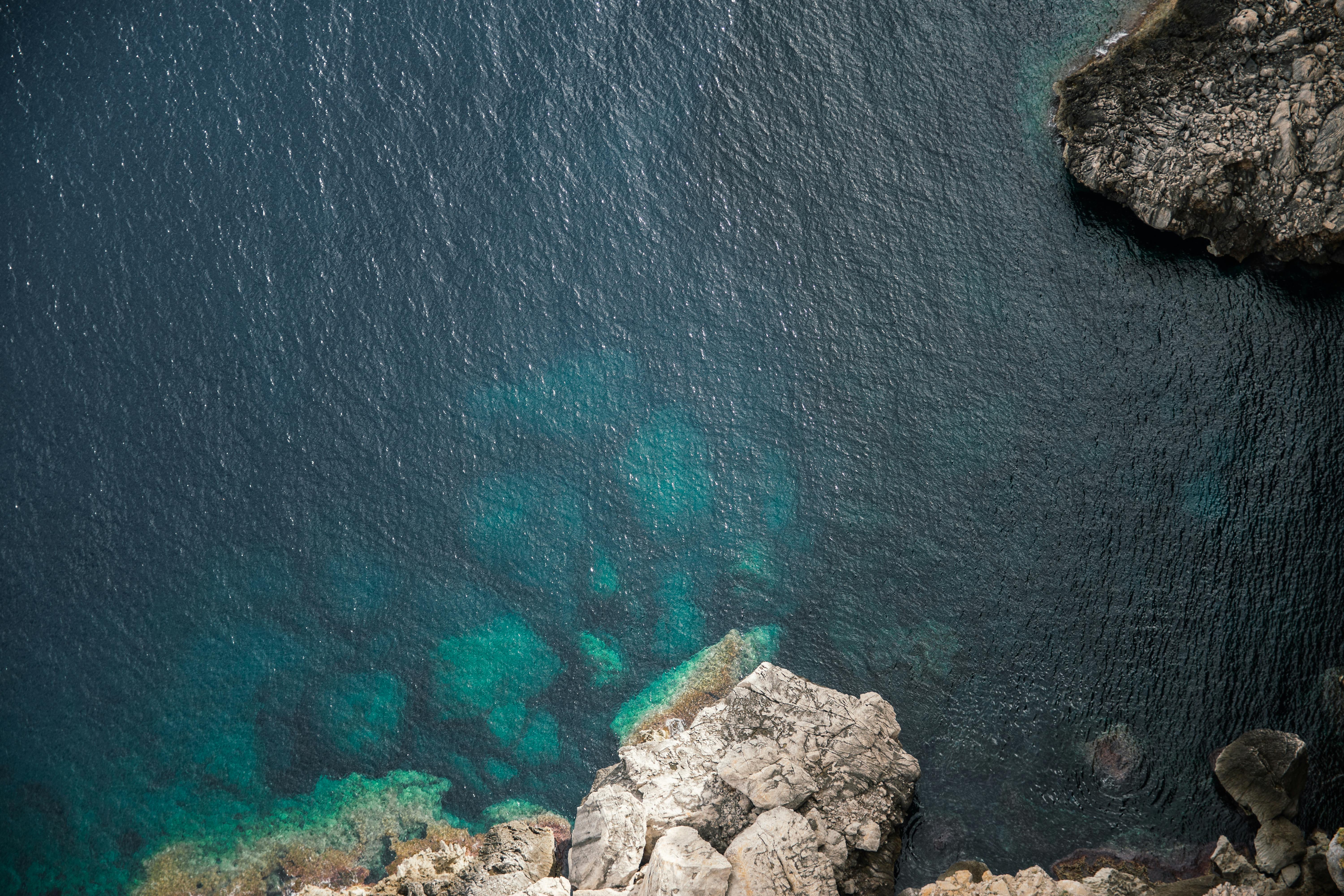 航拍镜头捕捉了岩石海岸线与深蓝色海水，凸显出自然美景