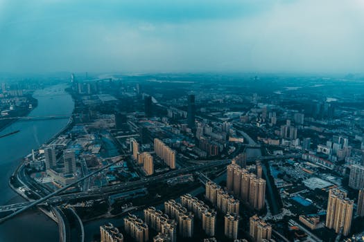 Aerial view of Guangzhou's urban landscape with skyscrapers and rivers during dusk.