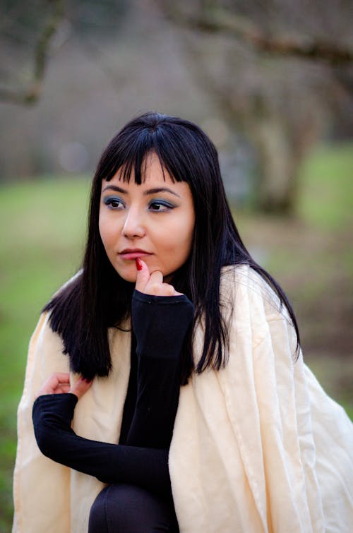 Young Brunette with Bangs Wearing a Coat in a Park 