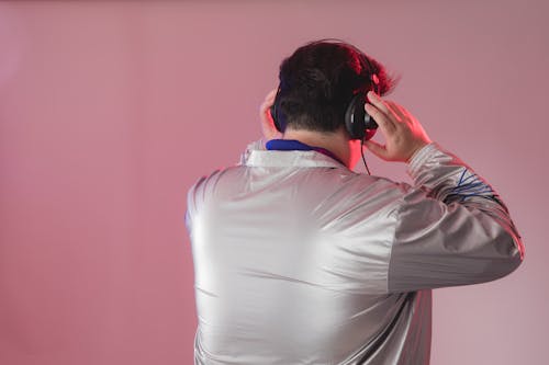 Back View of a Man in a Silver Jacket Wearing Headphones 