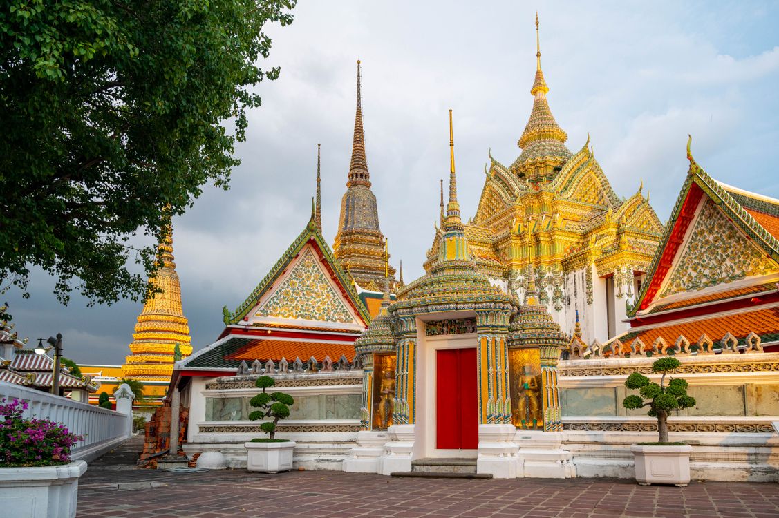 Colorful exterior view of Wat Pho temple in Bangkok, with its richly decorated stupas and traditional Thai architecture.