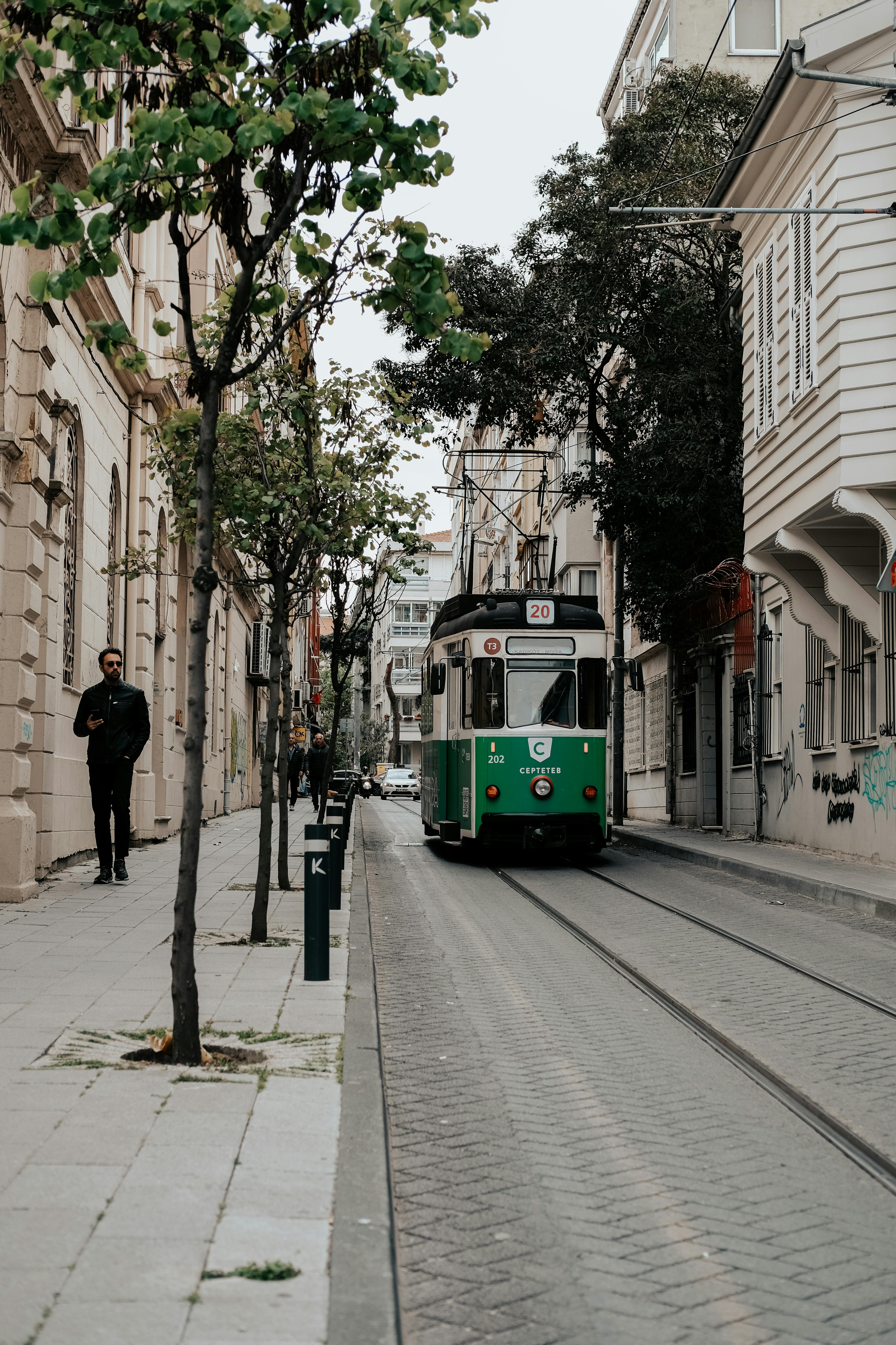A classic green tram navigating through a narrow street in Istanbul, Türkiye.