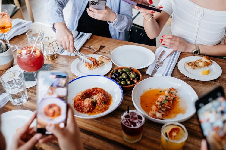 Women Taking Pictures Of The Food On The Table At The Restaurant 