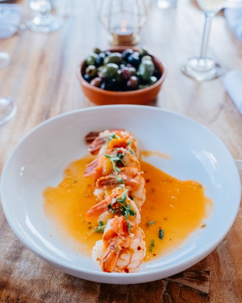 Free Delicious shrimp served in a sauce with mixed olives in the background, perfect for fine dining settings. Stock Photo