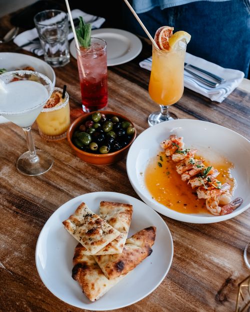 Free A restaurant table set with colorful cocktails, shrimp dish, and bread. Perfect for food and lifestyle themes. Stock Photo