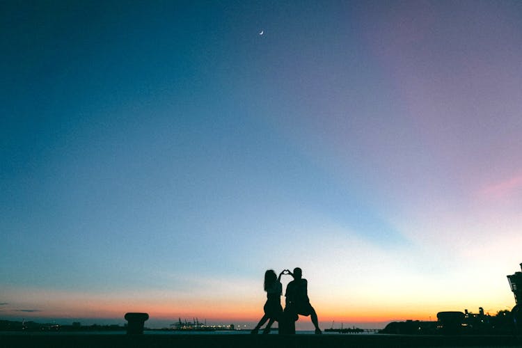 Couple Making Heart Shape On Coast At Sunset