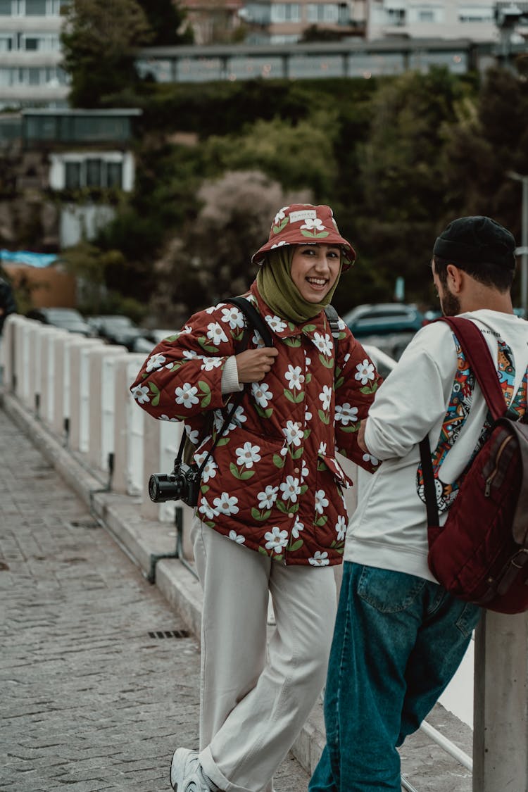 Smiling Woman In Hat And With Camera Standing With Man In Town