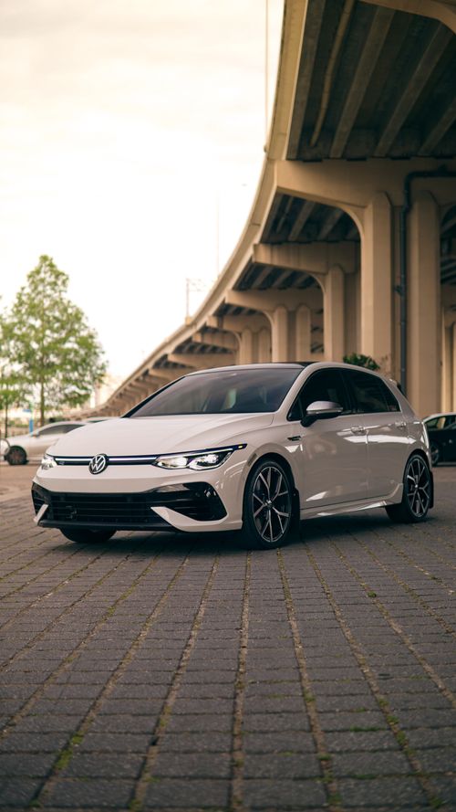 Free A white car parked under a large urban bridge on a paved surface during the day. Stock Photo