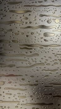 Detailed view of water droplets forming patterns on a metallic surface.