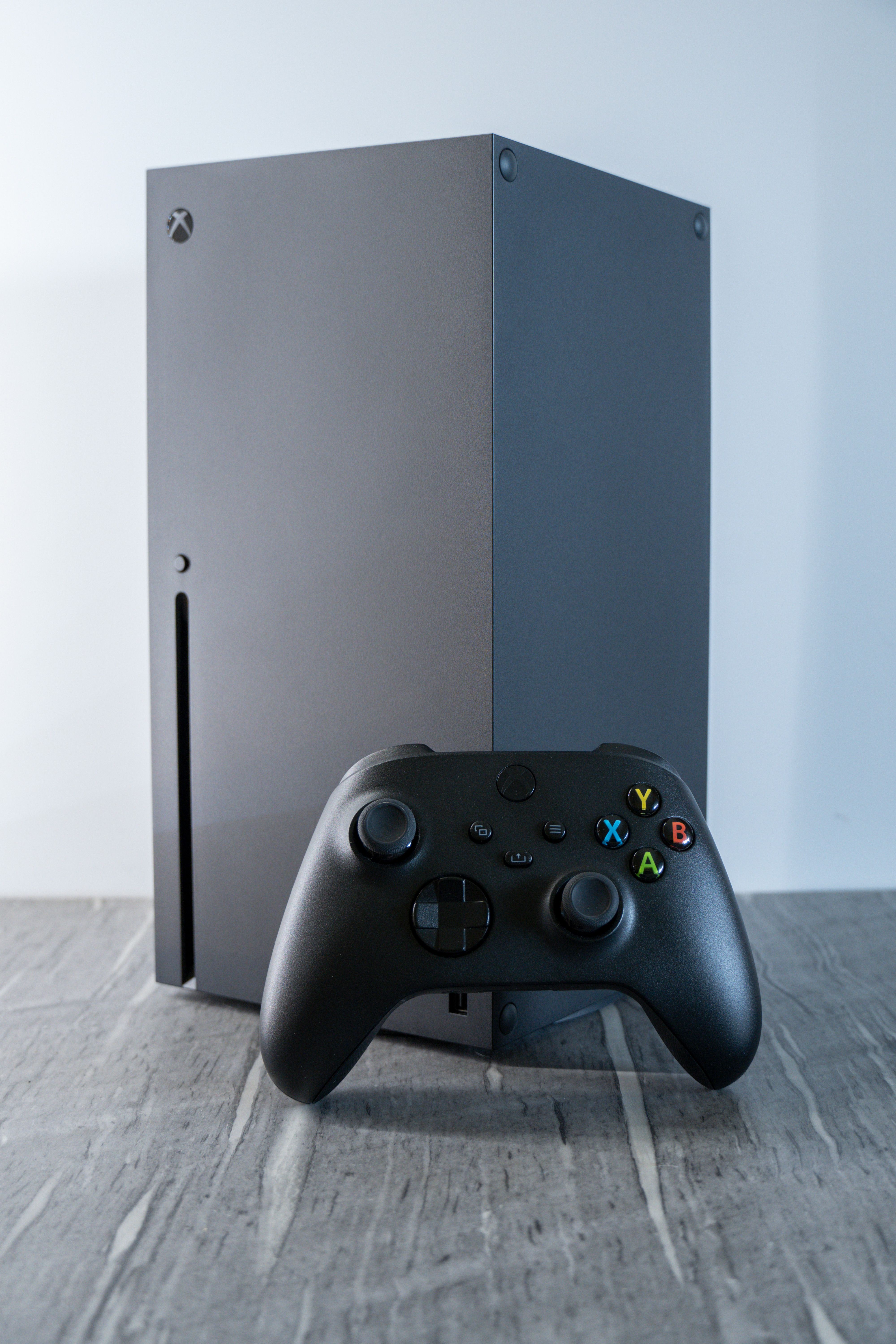 A close-up of a modern video game controller resting on a textured surface.