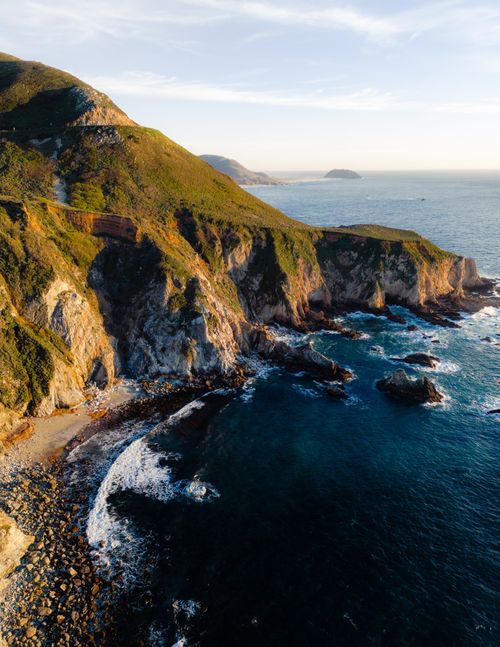 Free Breathtaking aerial view of rugged coastal cliffs with ocean waves below. Stock Photo
