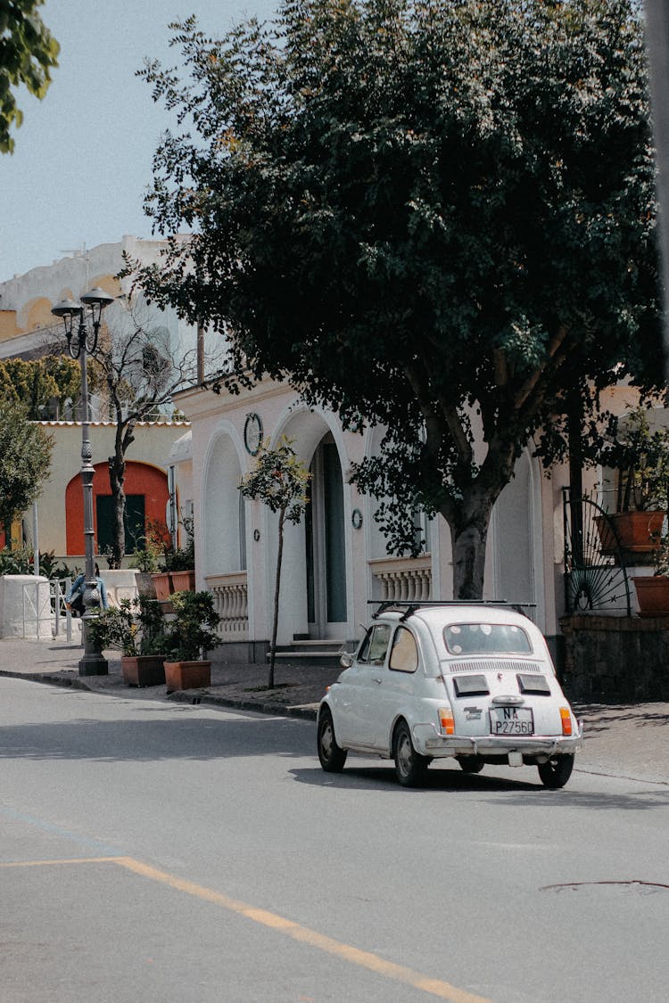 White Vintage Car Driving Along The Street In Summer