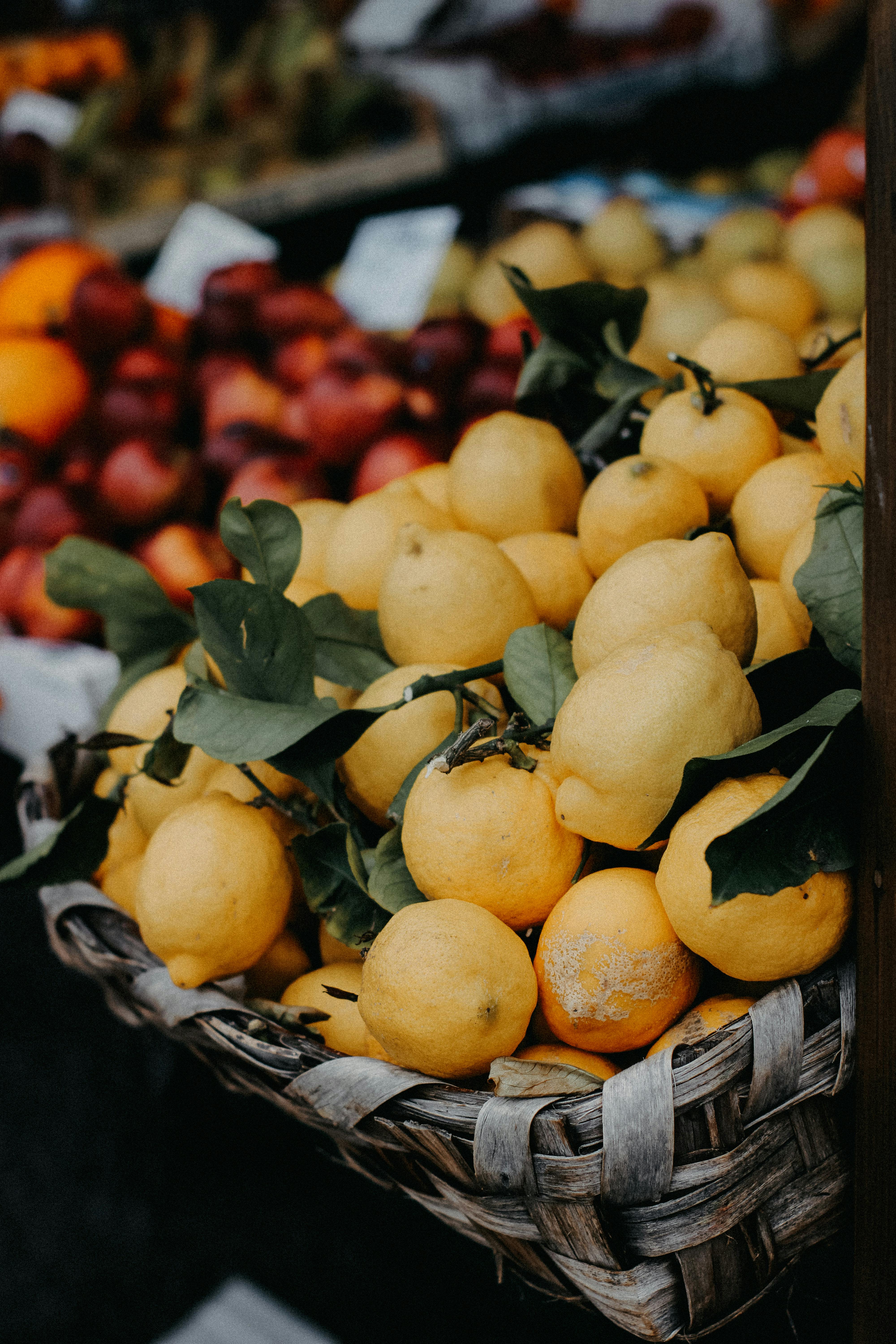 A vibrant shot of fresh lemons in a rustic basket at an outdoor market. Perfect for culinary themes.