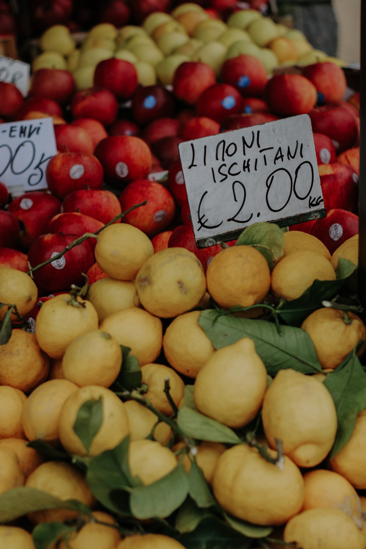 Fresh lemons and apples with price tags at a market stall