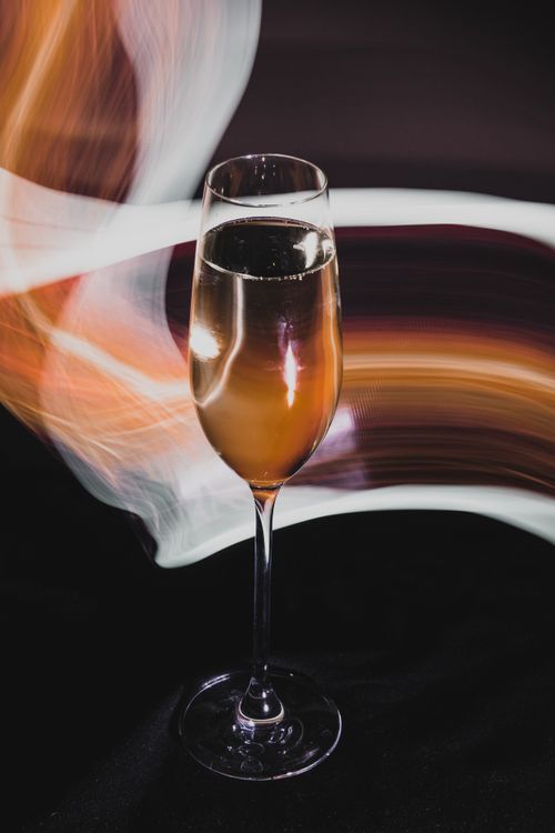 Free Stylish champagne glass with dynamic light trails creating an artistic ambiance. Stock Photo