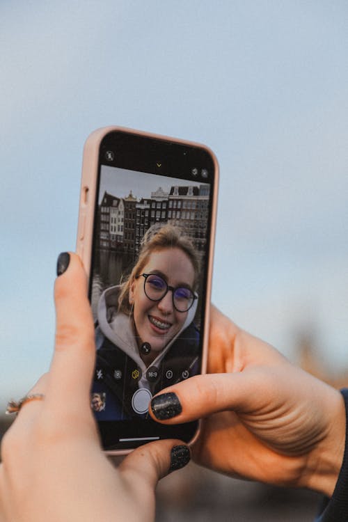 Young Woman Holding a Smart Phone with her Selfie on the Screen 