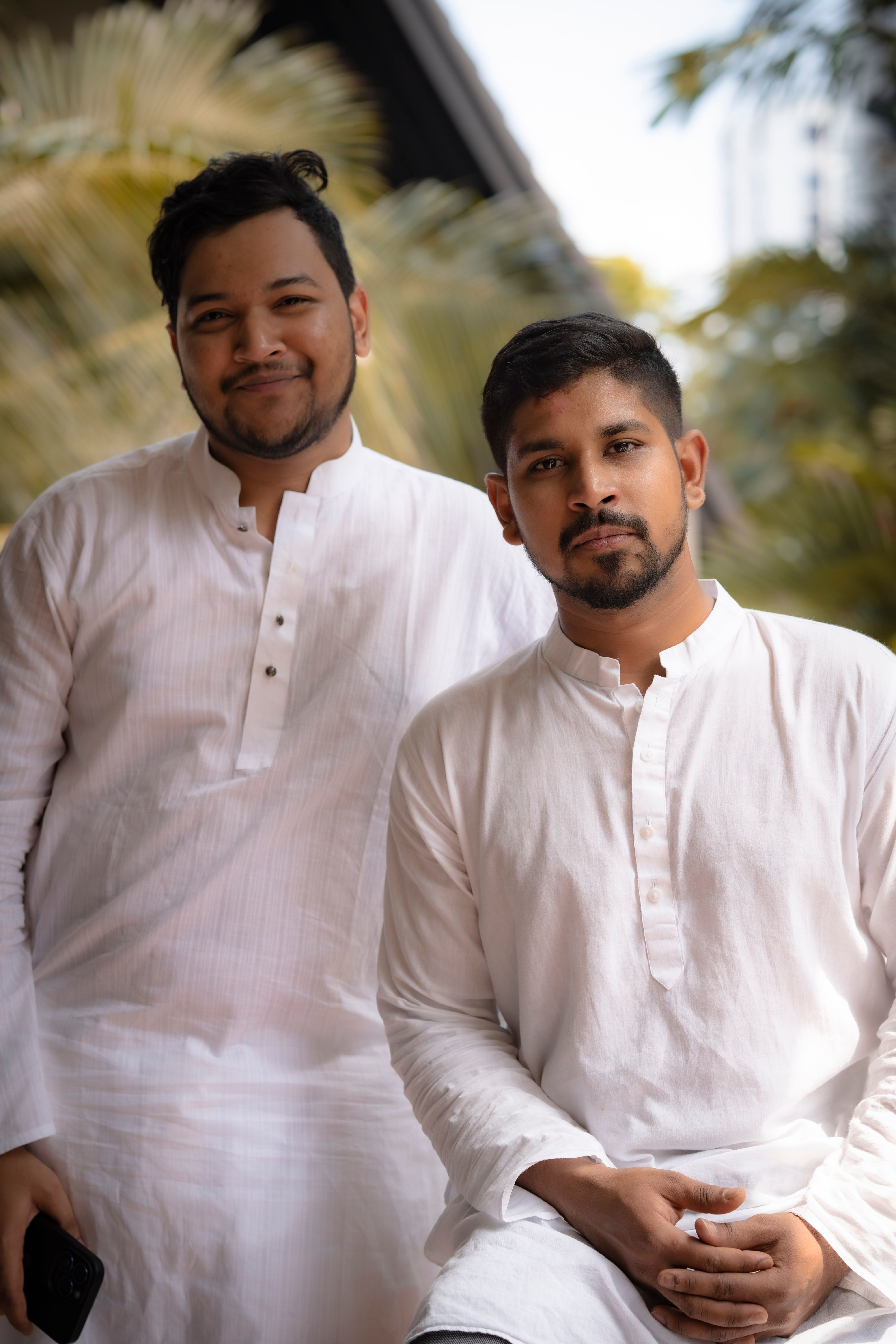 Two men in traditional white kurtas posing outdoors, showcasing ethnic Indian fashion and culture.