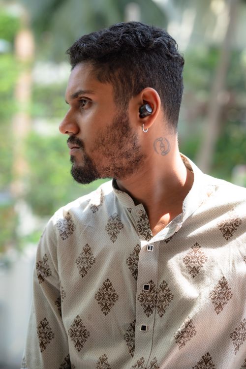 Free Portrait of a young man wearing wireless earbuds, outdoors, in a casual outfit. Stock Photo