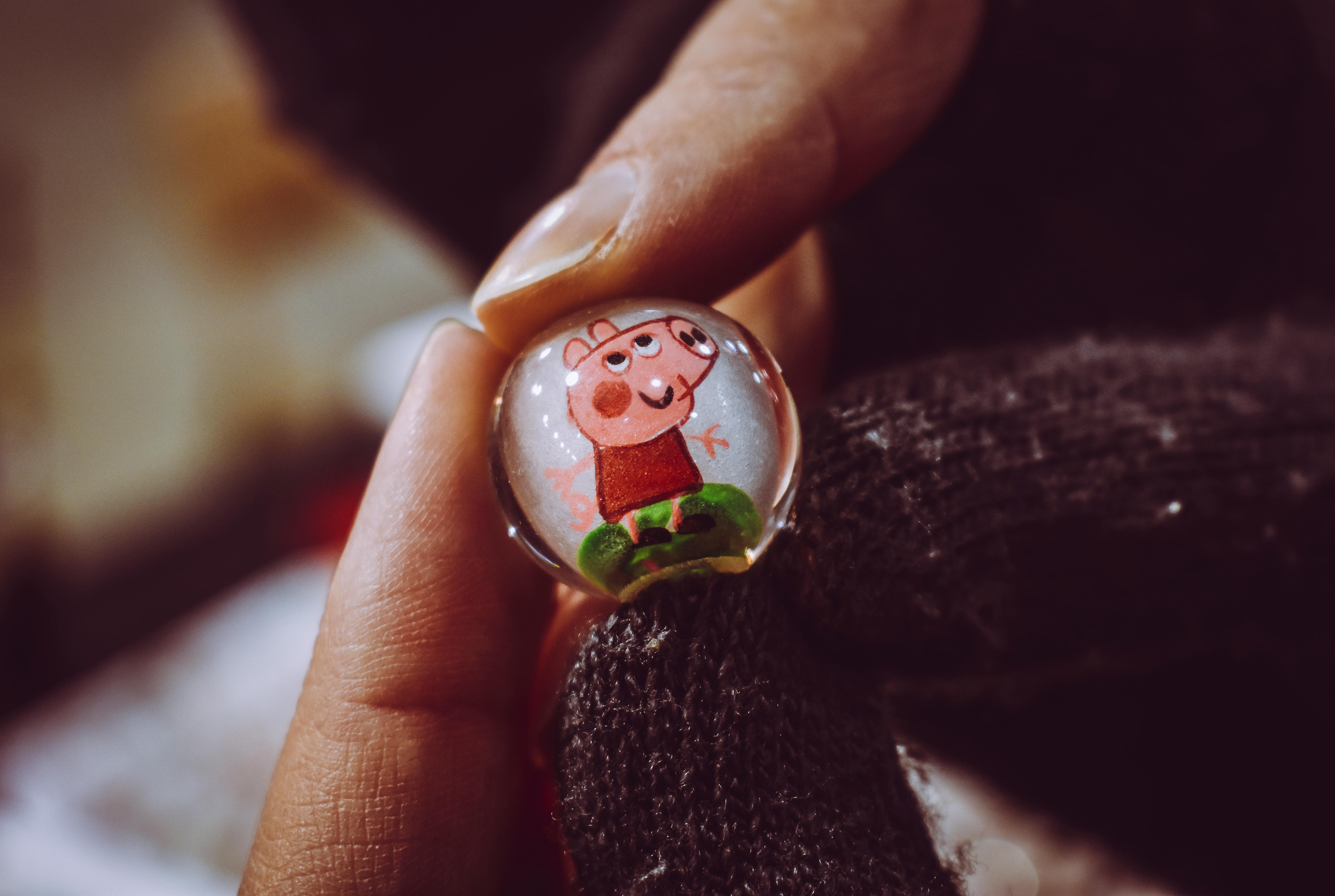 person holding peppa pig toy marble