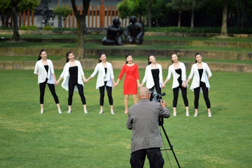 Man Photographing Woman in Red Dress and her Friends