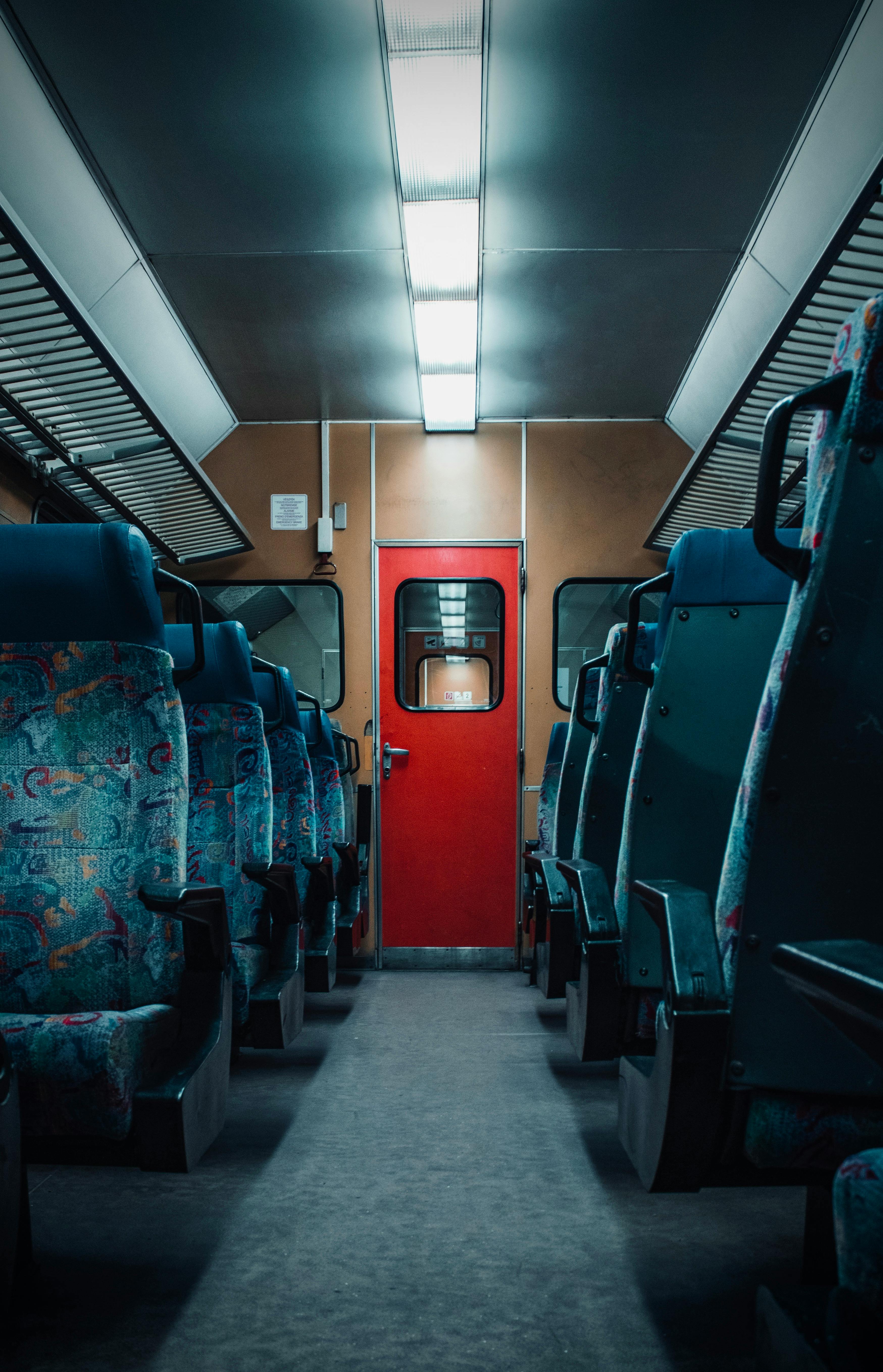 A detailed look at an empty train carriage with blue seats and a red door.
