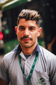 Close-up portrait of a man with short hair wearing a lanyard outdoors. Natural light.