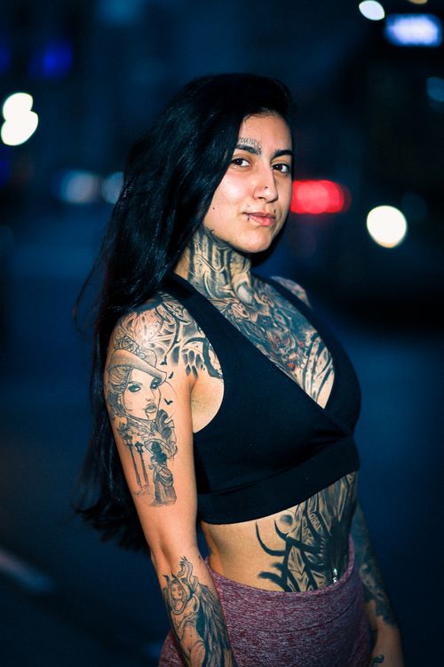 Free A confident tattooed woman poses stylishly in an urban night setting. Stock Photo