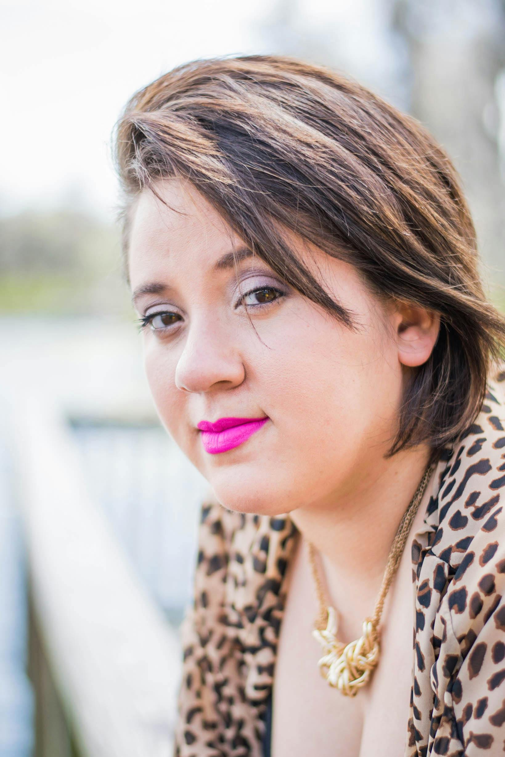 一位时尚女士在户外摆出豹纹图案，涂着鲜艳的口红，散发着自信