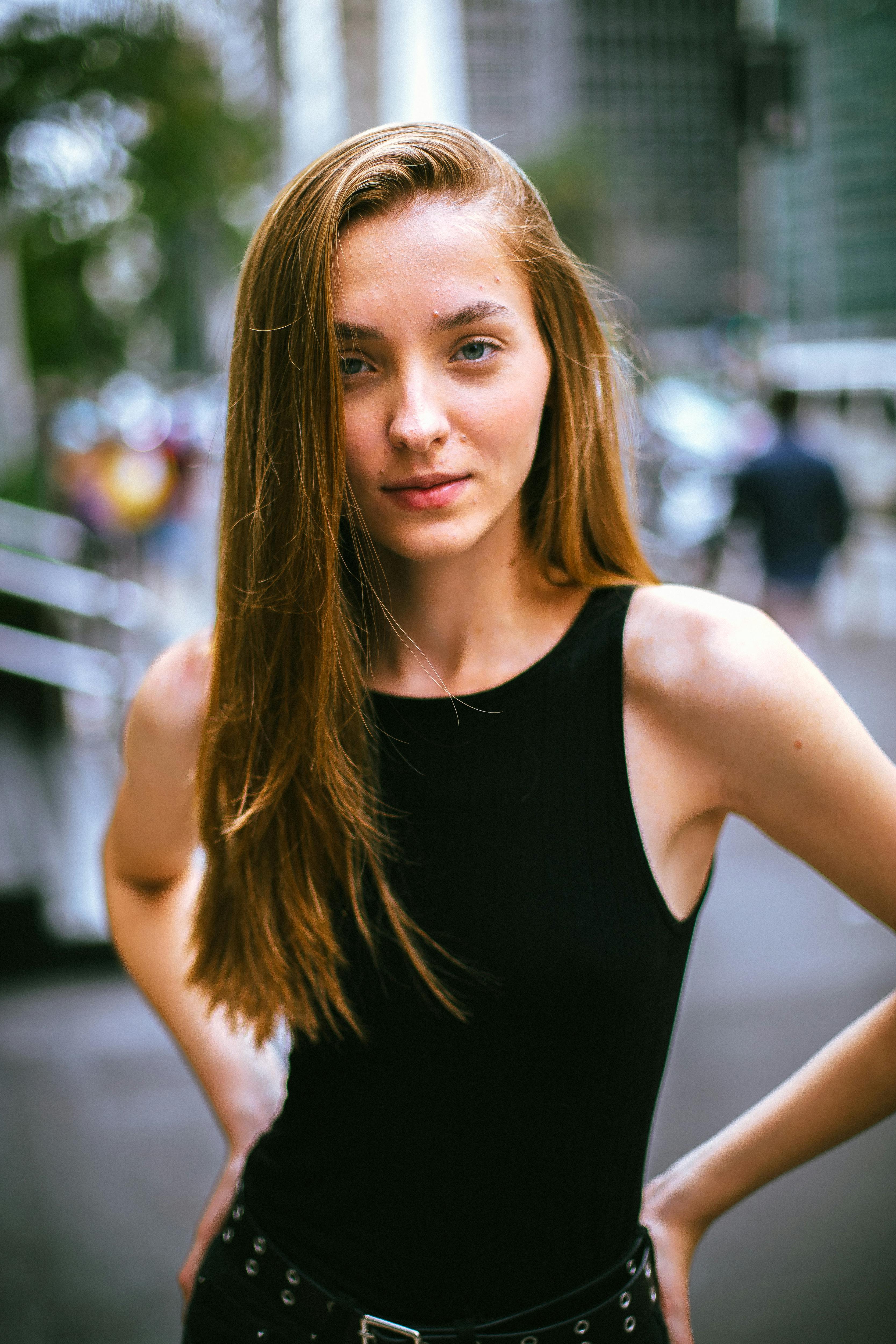 A fashionable young woman poses confidently in a busy urban setting.