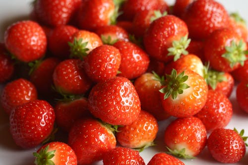 A close up of a pile of strawberries