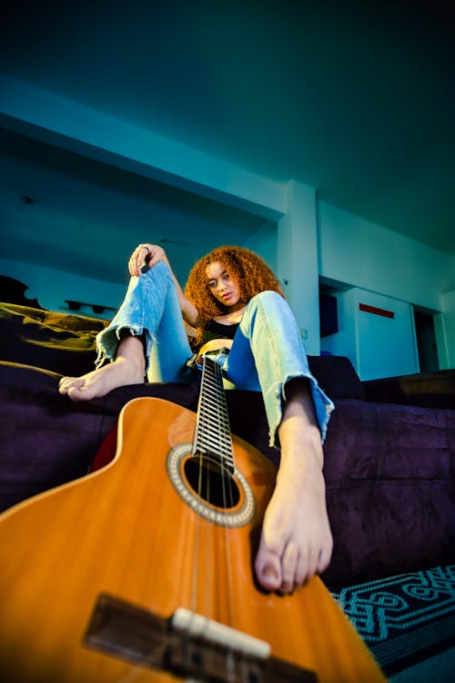Low Angle Shot of a Woman Sitting on the Couch and Holding a Guitar 