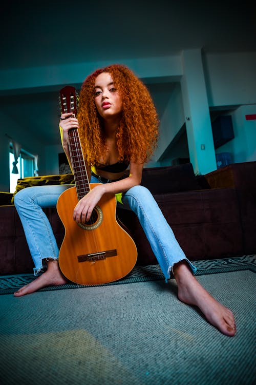 Woman Sitting on the Sofa and Holding a Guitar