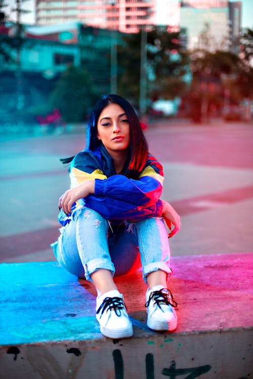 Woman in Ripped Jeans Sitting on the Concrete Bench 
