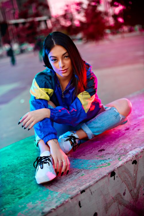 Free Dynamic shot of a young woman in vibrant clothing posing in an urban setting. Stock Photo