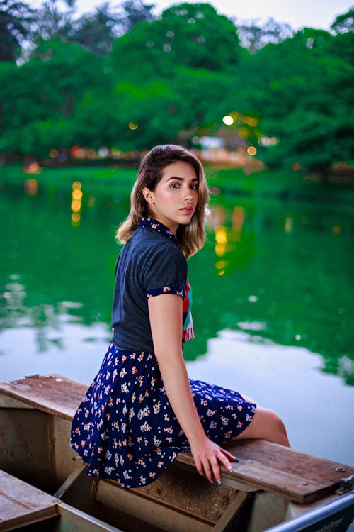 Young Woman in a Summer Dress Sitting by the Lake 
