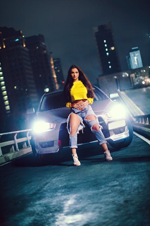 Young Woman Posing near Car on Road at Night