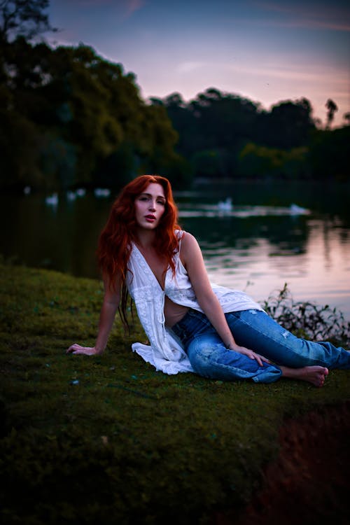 Young Woman Sitting on a Lakeshore at Dusk 