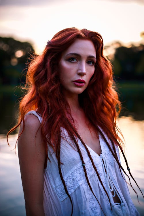 Young Woman in a White Blouse Posing in front of a Lake at Dusk 