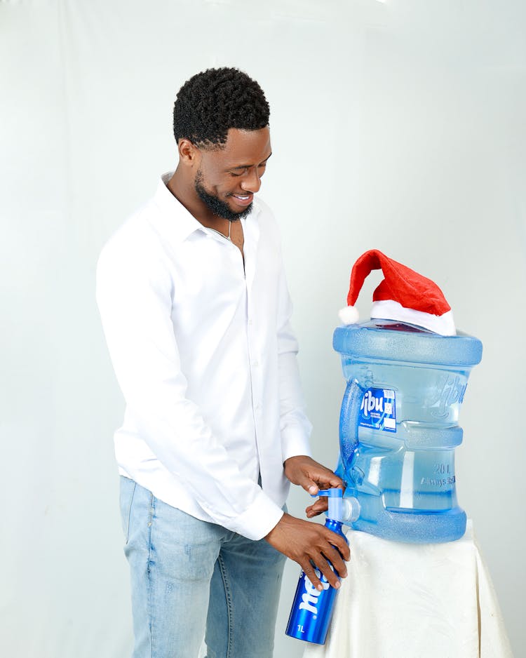 Smiling Man Pouring Water In Bottle From Cooler