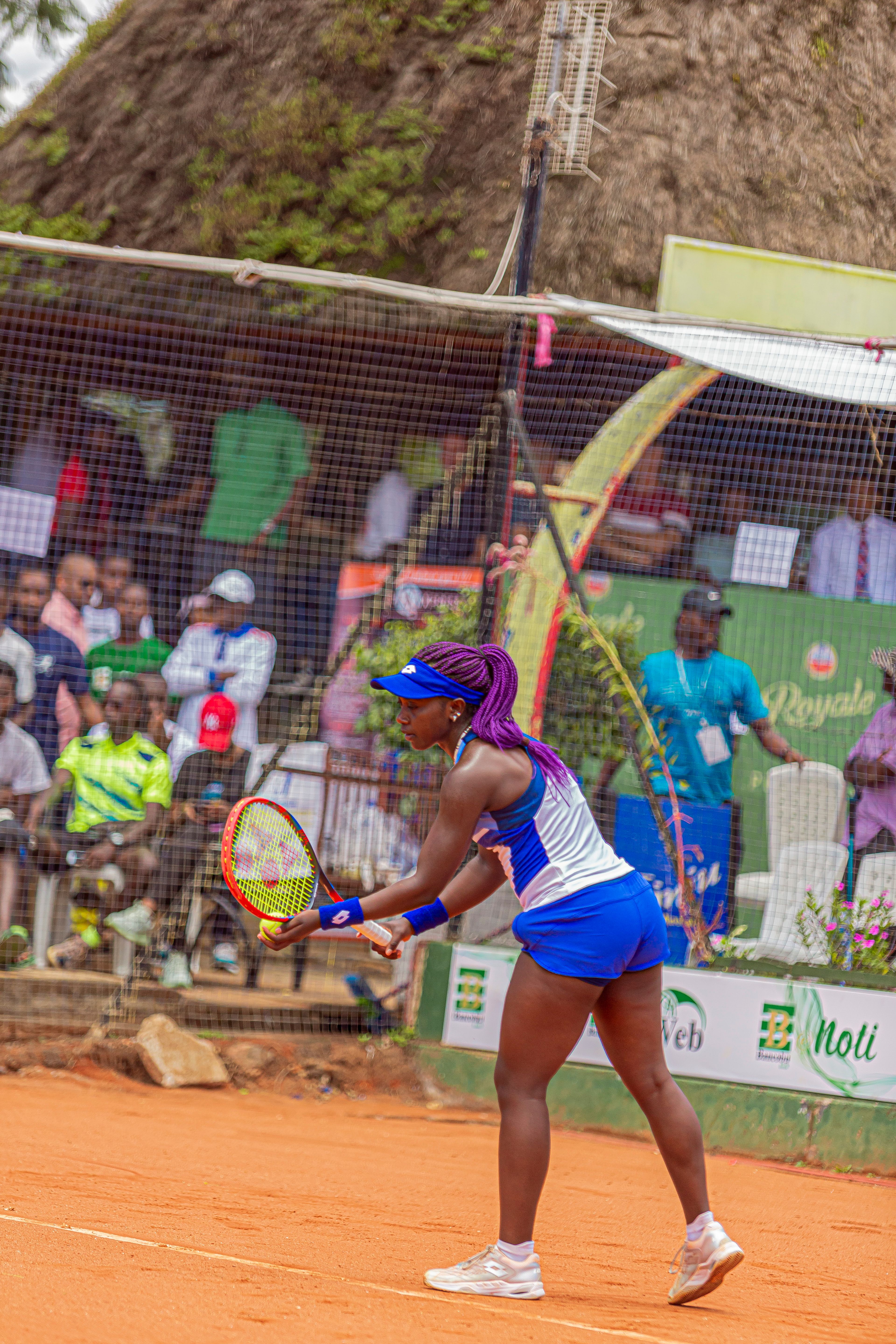 African American woman playing tennis on a professional clay court outdoors.