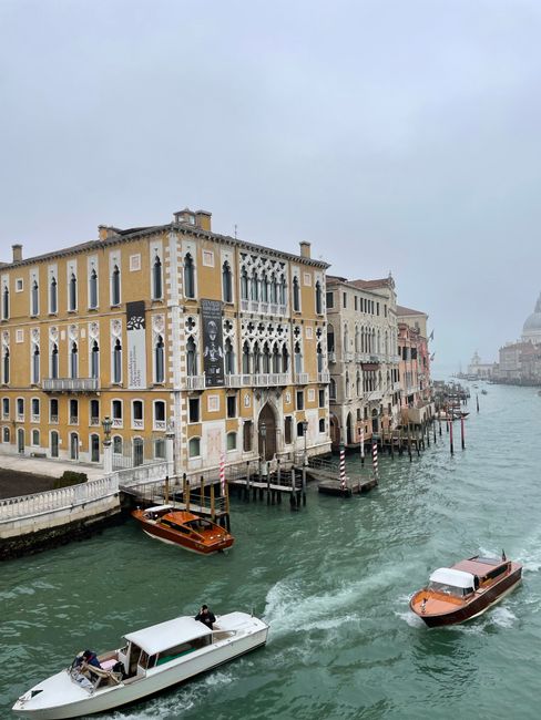 Scenic view of Venice canal with boats and historic architecture in a misty atmosphere.