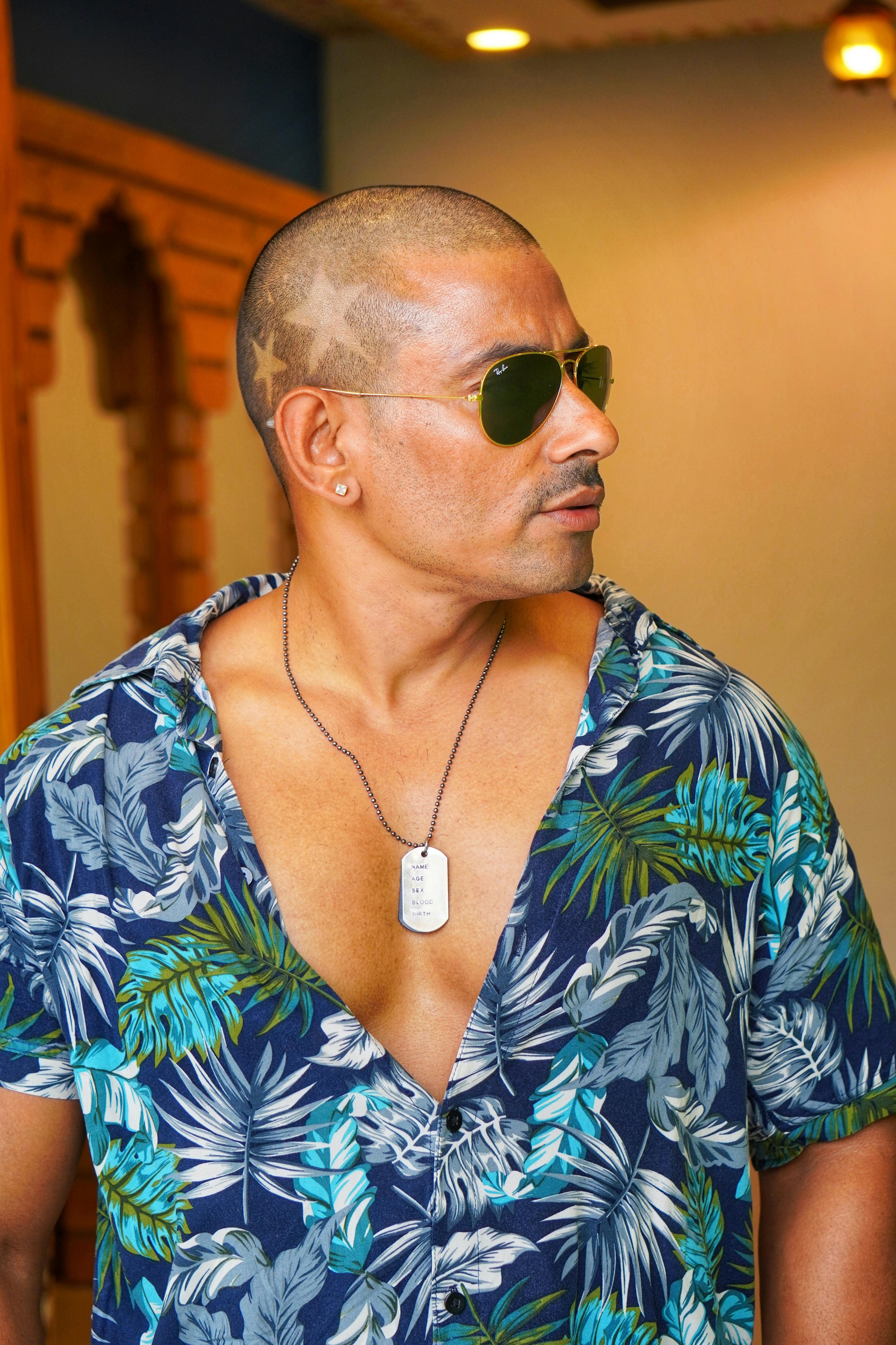 Free Stylish man with sunglasses and floral shirt, embracing summer fashion indoors. Stock Photo